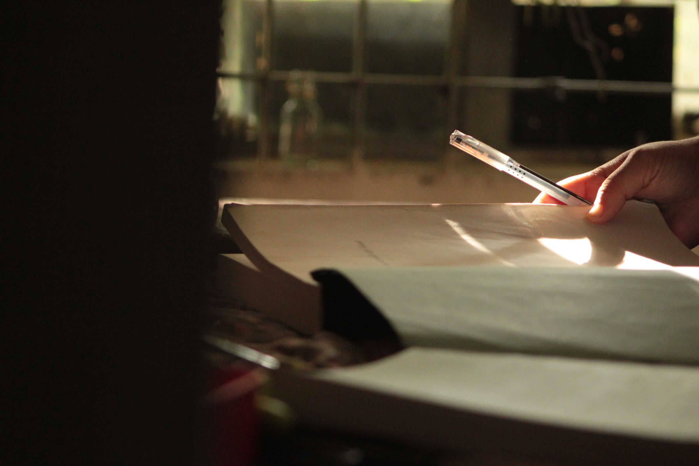 A student solving mathematics problems in a notebook near a window