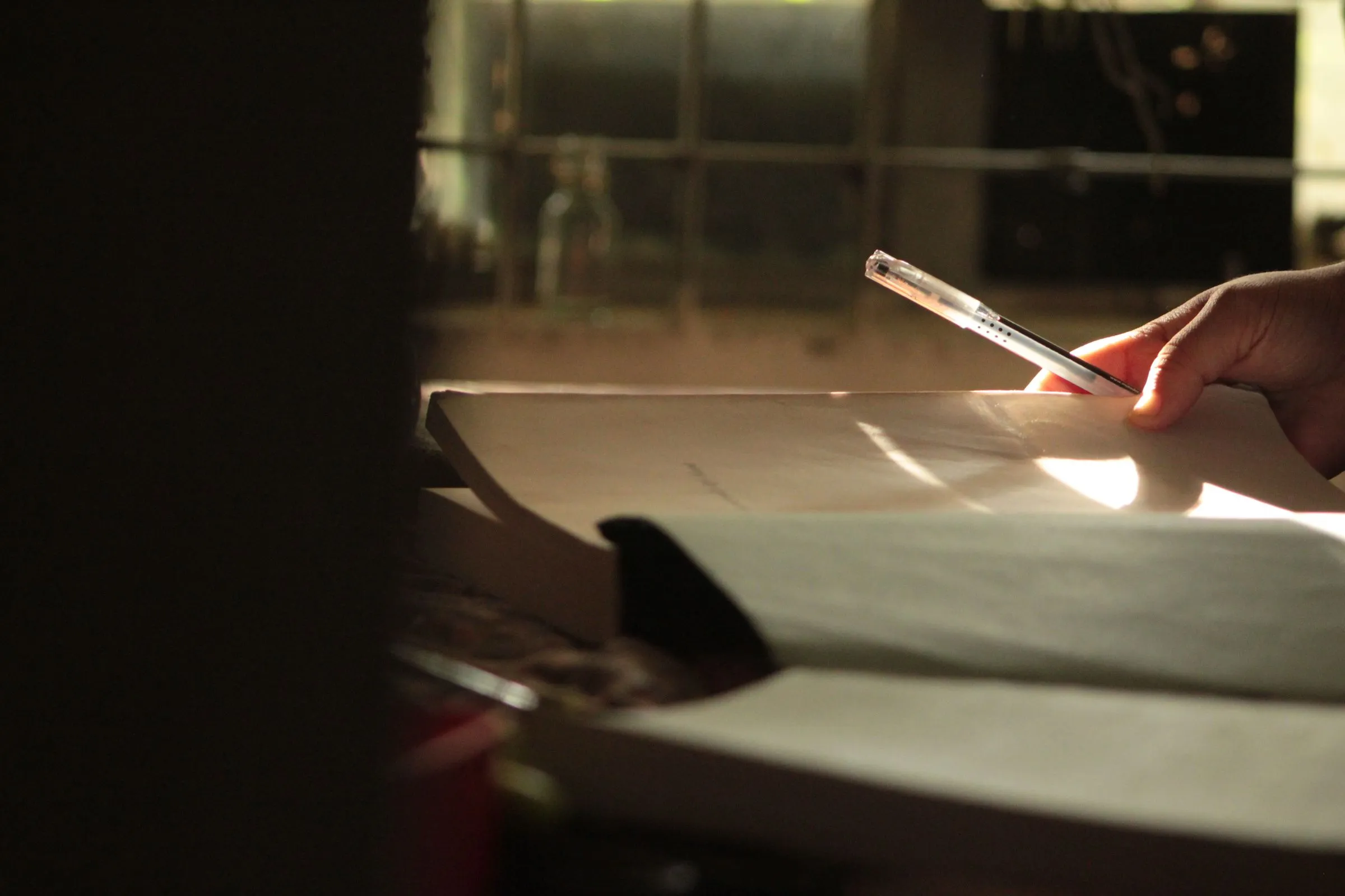 A student writing notes beside a sunlit window
